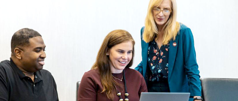 Employees reviewing content on laptop.