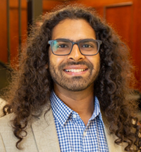 Sarfaraz Serang smiles at the camera, wearing a blue button down shirt and a dark blue blazer.