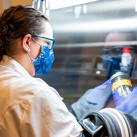 grad student works in a lab under a hood