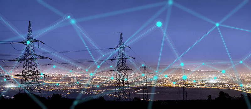 Stock photo of power lines heading toward a city.