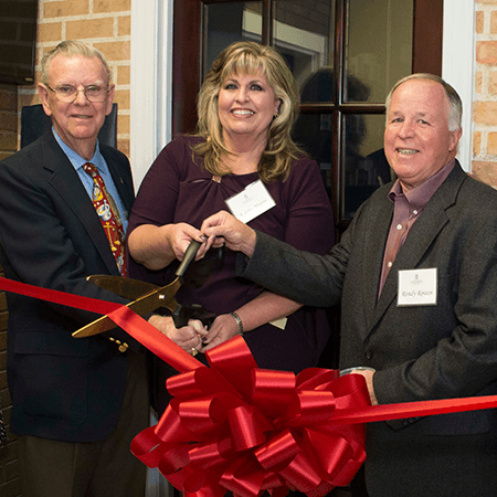 Three people at a ribbon cutting