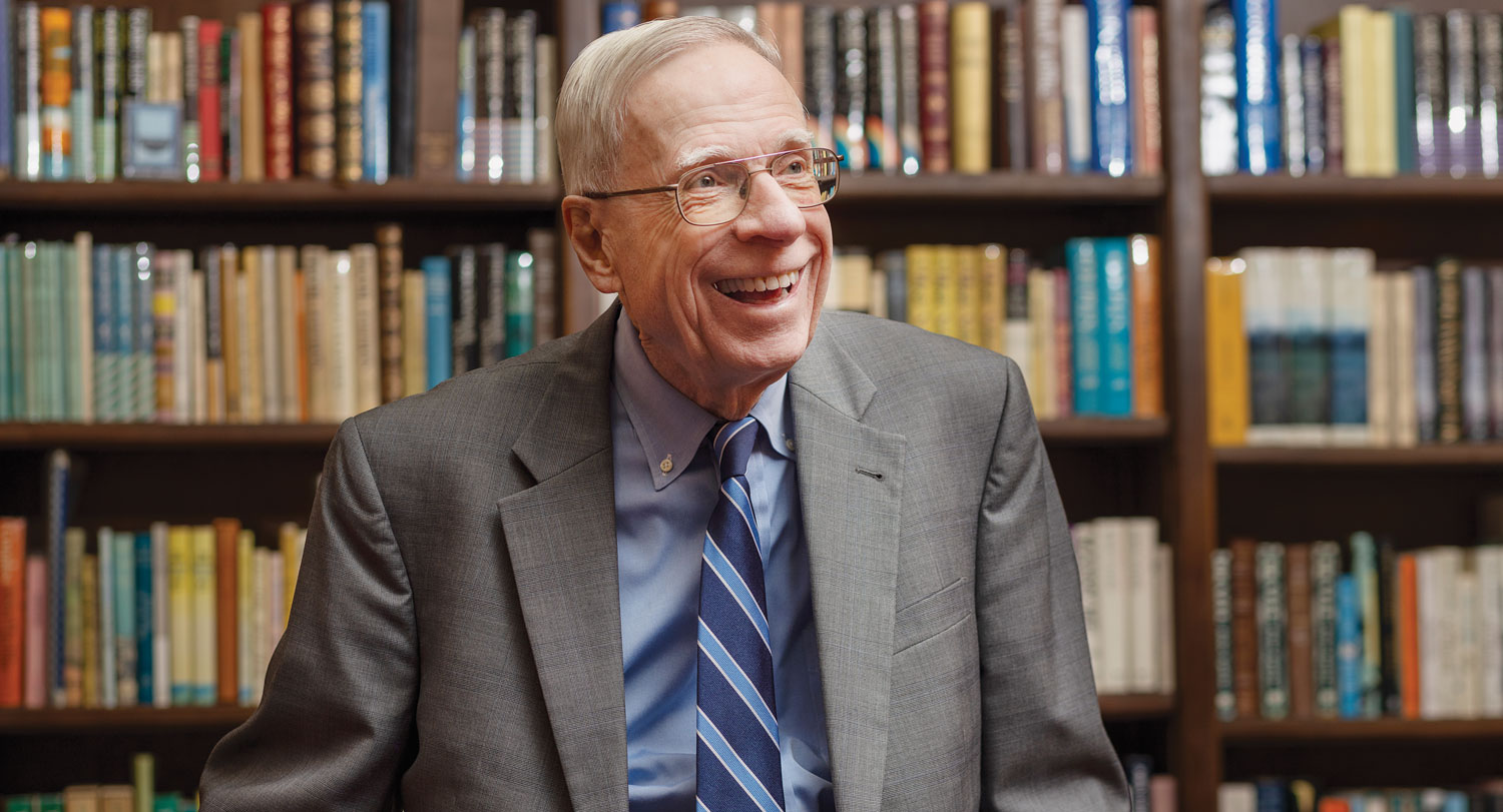 A headshot of Don Greiner in his office with filled bookshelves behind him.