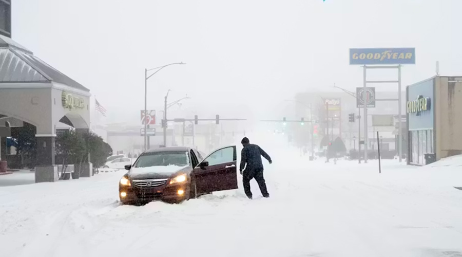 A driver exiting a stalled car on a snowy street.
