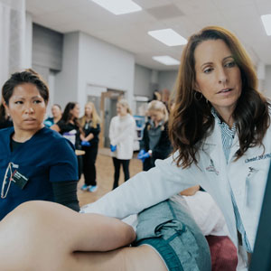 A nurse practitioner student watches nursing associate professor Amy Dievendorf demonstrate an ultrasound monitor.