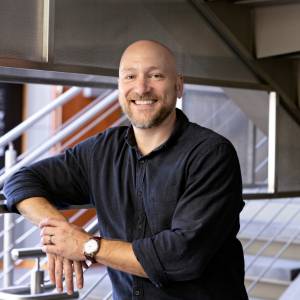 Aaron Vannucci stands by a staircase and smiles.