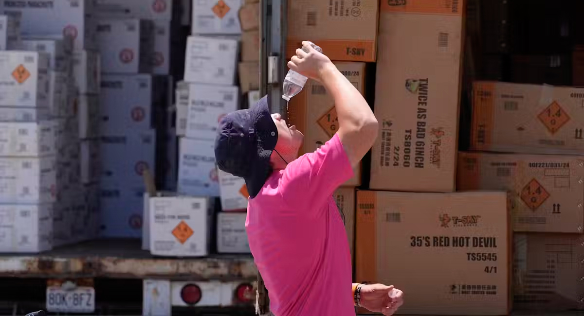 Male takes break from loading boxes to drink from bottle of water.