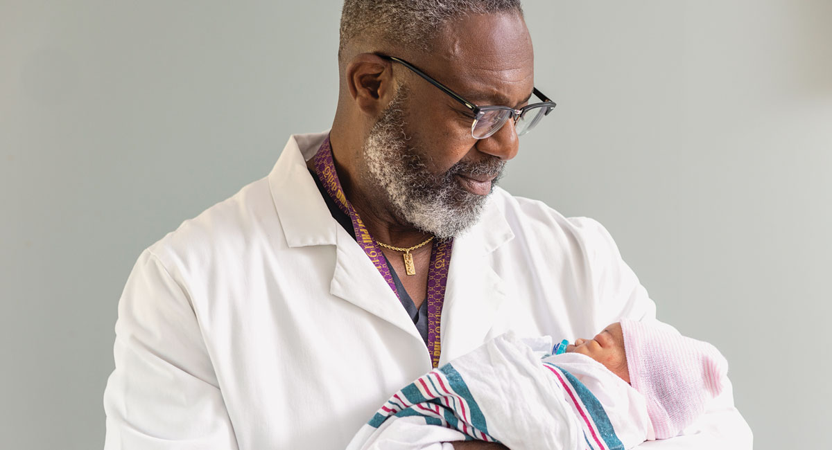 Dr. Leroy Robinson holds a newborn baby.