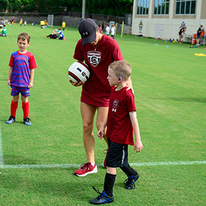 an adult with children on a soccer field 